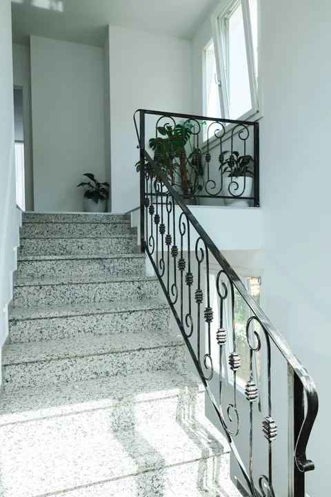 Terrazzo staircase with an ornate wrought-iron railing and potted plants