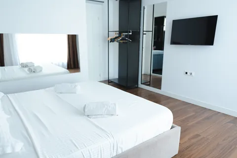 Bedroom with a wall-mounted TV, open wardrobe rail and wooden floors