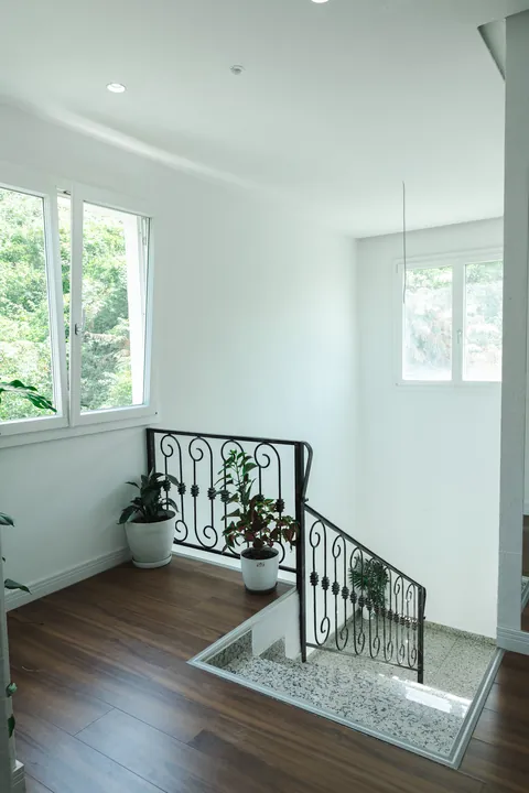 Upper landing with wooden floors, a wrought-iron balustrade and windows onto the trees