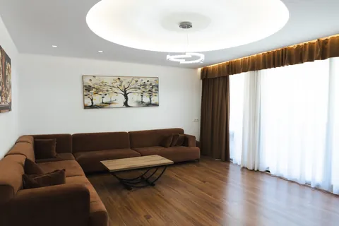 Living room with a large brown velvet sectional sofa, wooden coffee table and floor-length curtains