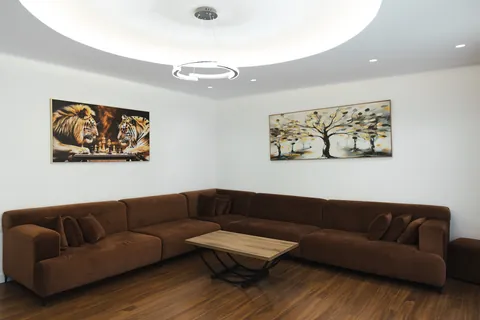 Living room with a softly lit circular ceiling, framed artwork and a corner sofa