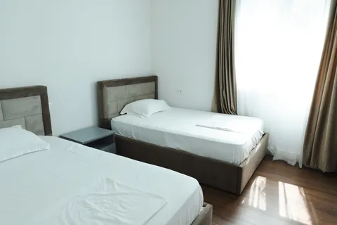 Bedroom with upholstered headboards and soft natural light through long curtains