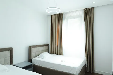 Bright twin bedroom with a ring pendant light and long curtains