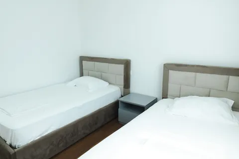 Single beds with upholstered headboards and white linens