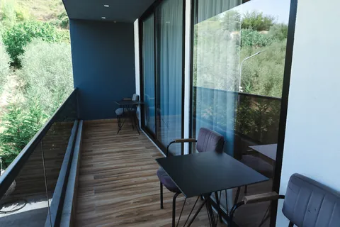 Balcony seating area with a glass railing overlooking trees and greenery