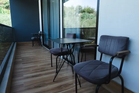 Balcony table and upholstered chairs beside full-height glass doors