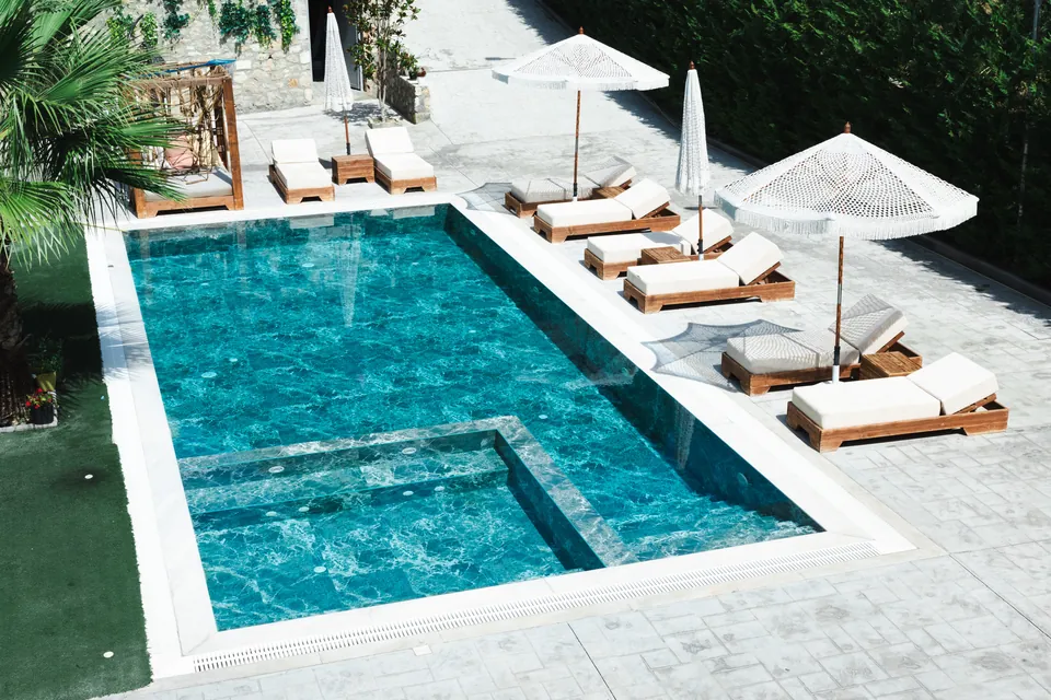 Rows of cushioned sun loungers and white parasols along the pool edge